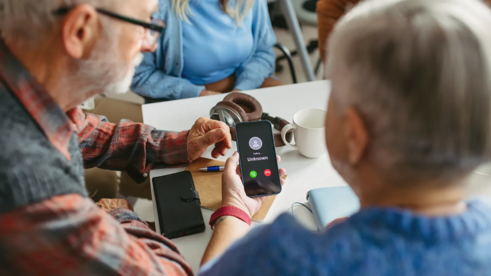 Senior couple looking at smartphone showing an incoming call from an unknown caller during a meeting.