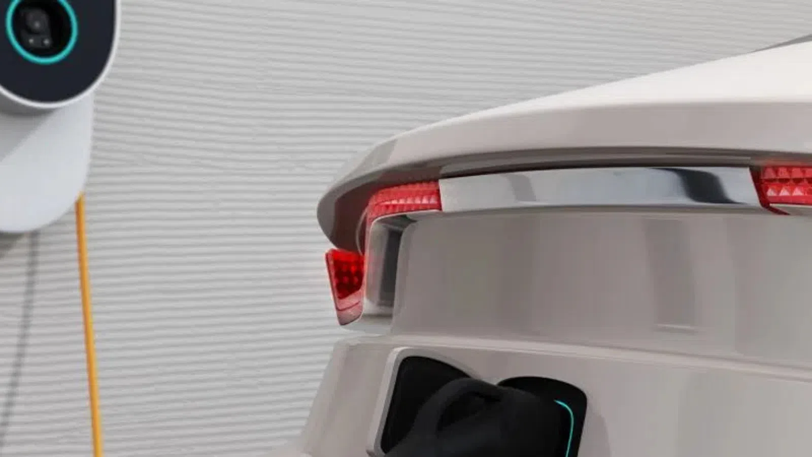 Electric car rear with charging port connected to wall-mounted EV charger with yellow cable indoors.