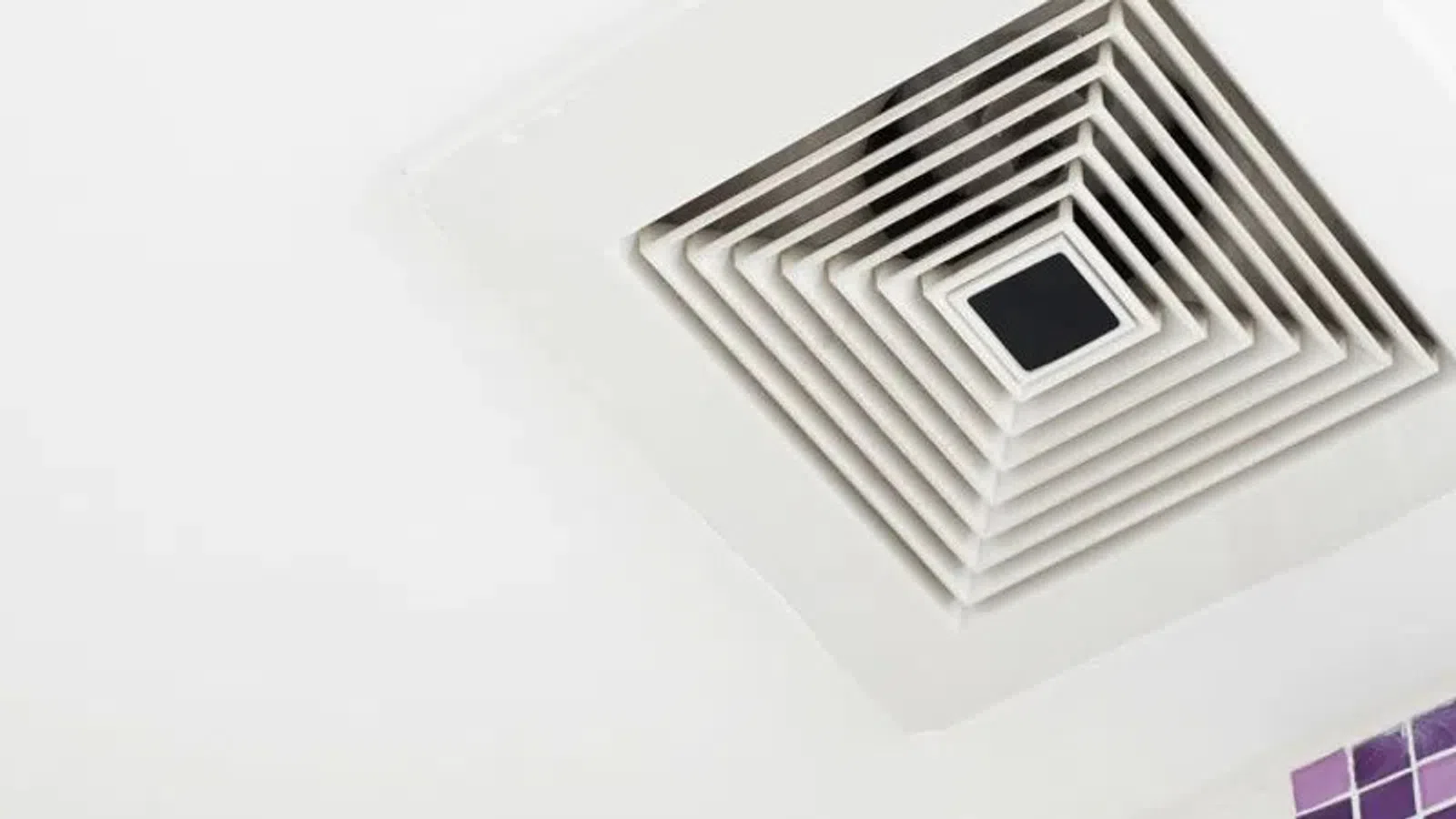 White ceiling air vent diffuser in a clean modern room with part of tiled wall visible