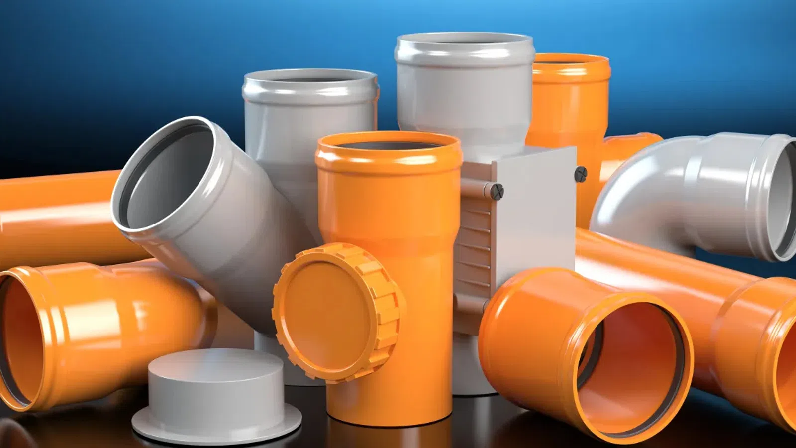 Various orange and gray plastic plumbing pipes and fittings arranged on a black reflective surface.