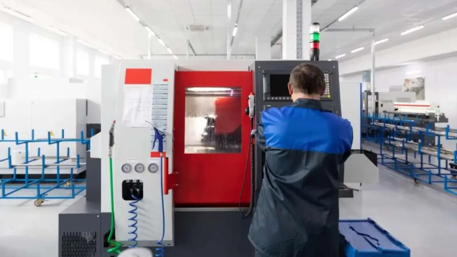 Technician operating CNC machine in a modern, bright industrial workshop with organized equipment.
