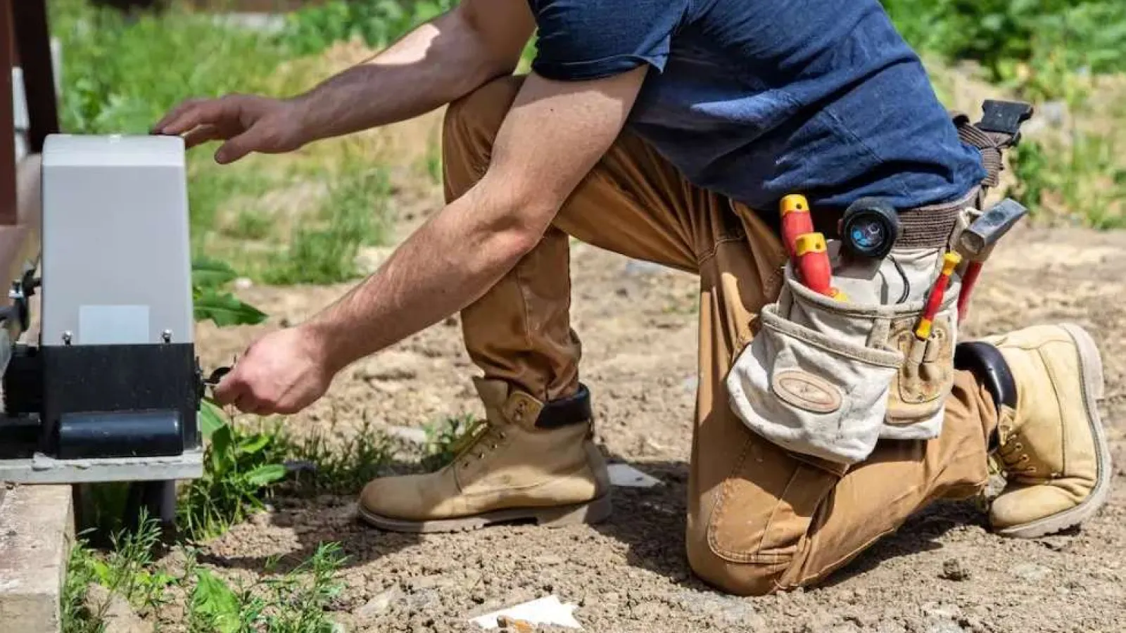 Technician with glasses inspecting and repairing an outdoor HVAC unit during daytime.