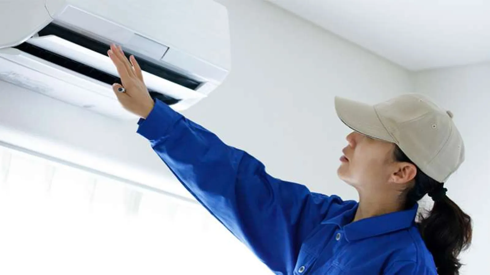 Hand pressing the power switch on a white electric heater in a cozy indoor setting.