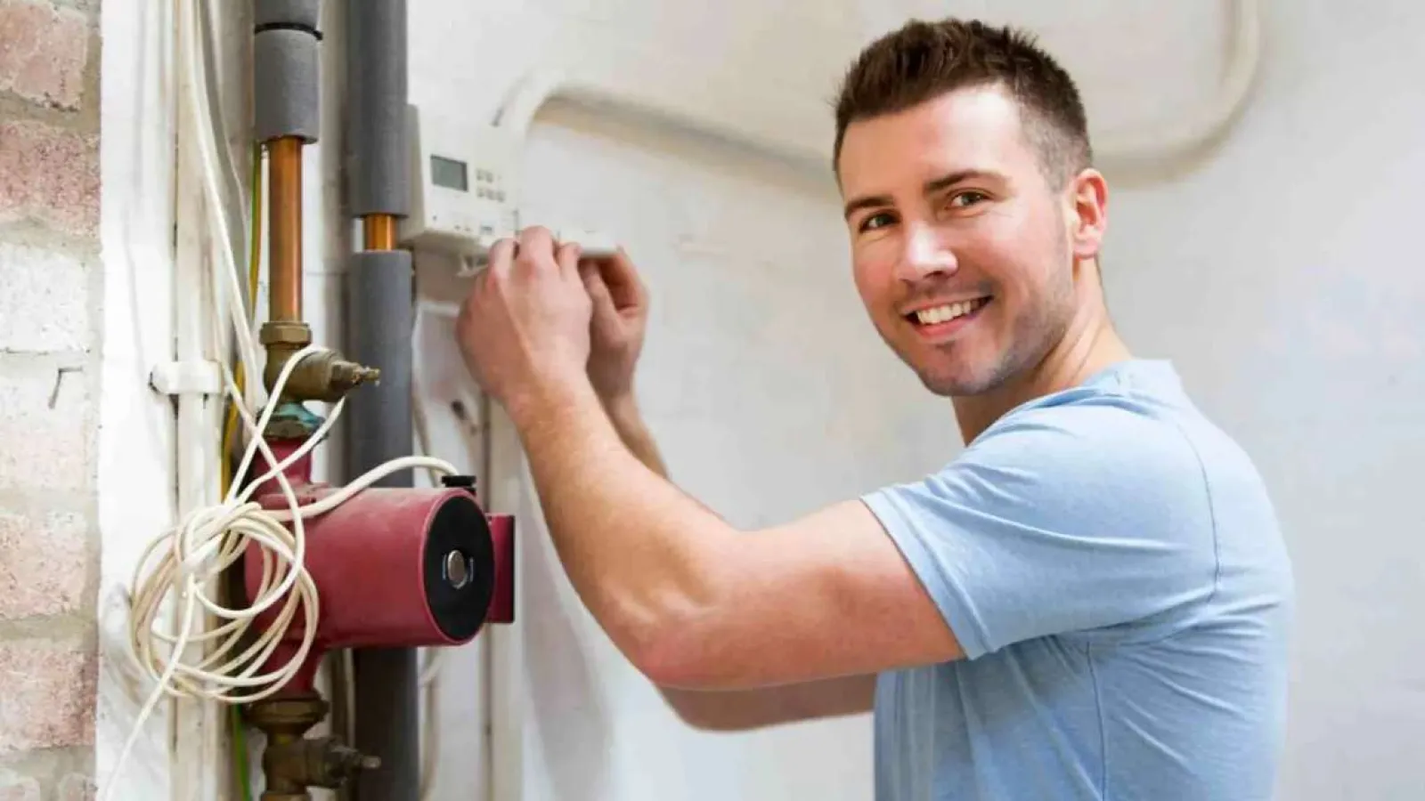 Technician with glasses inspecting and repairing an outdoor HVAC unit during daytime.