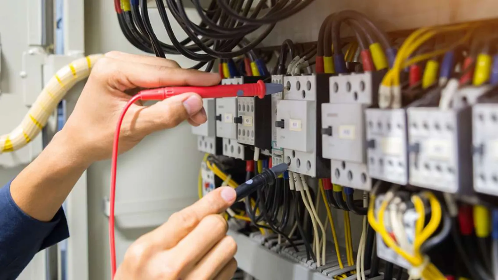 Technician with glasses inspecting and repairing an outdoor HVAC unit during daytime.