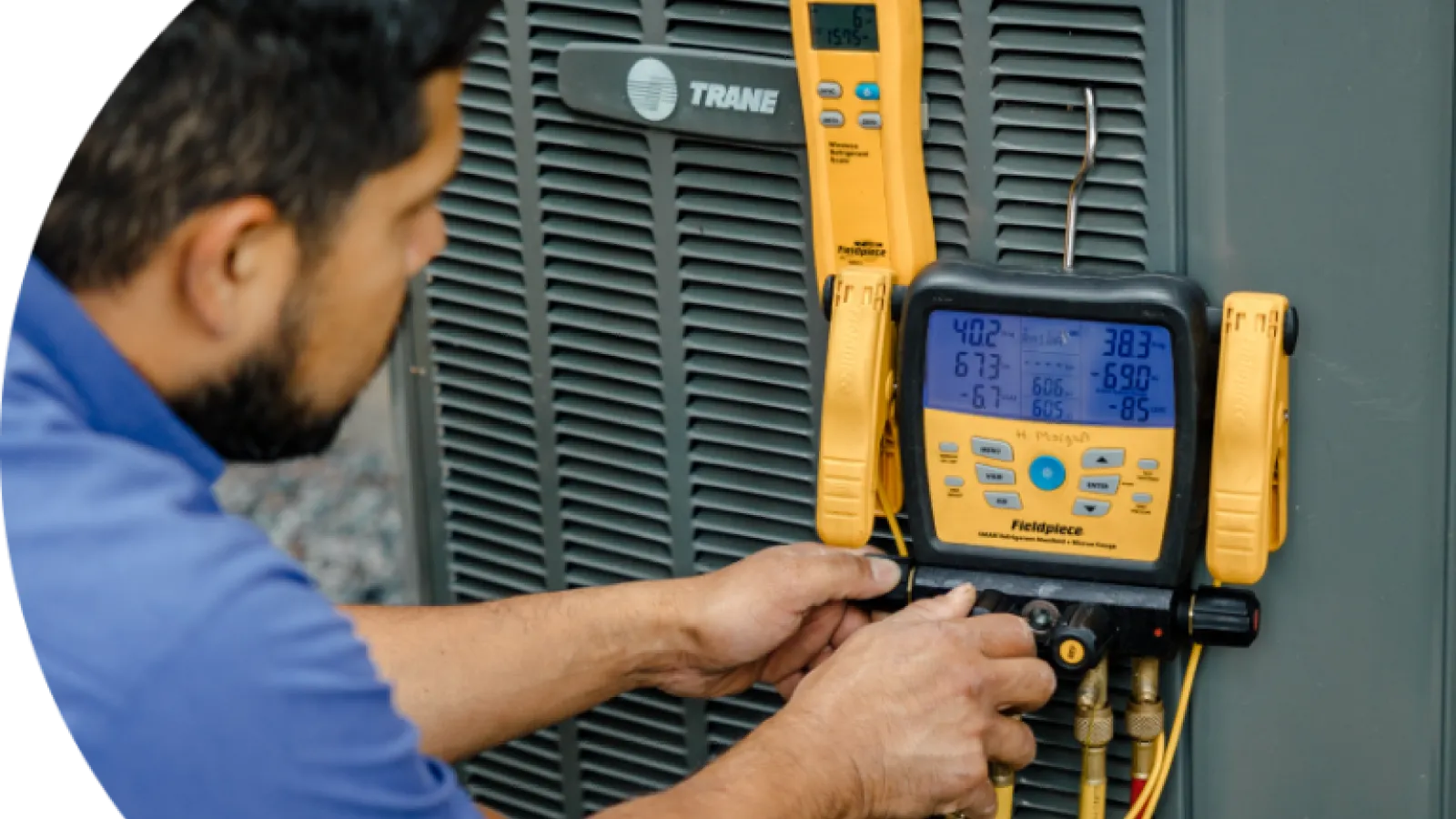 Hand pressing the power switch on a white electric heater in a cozy indoor setting.