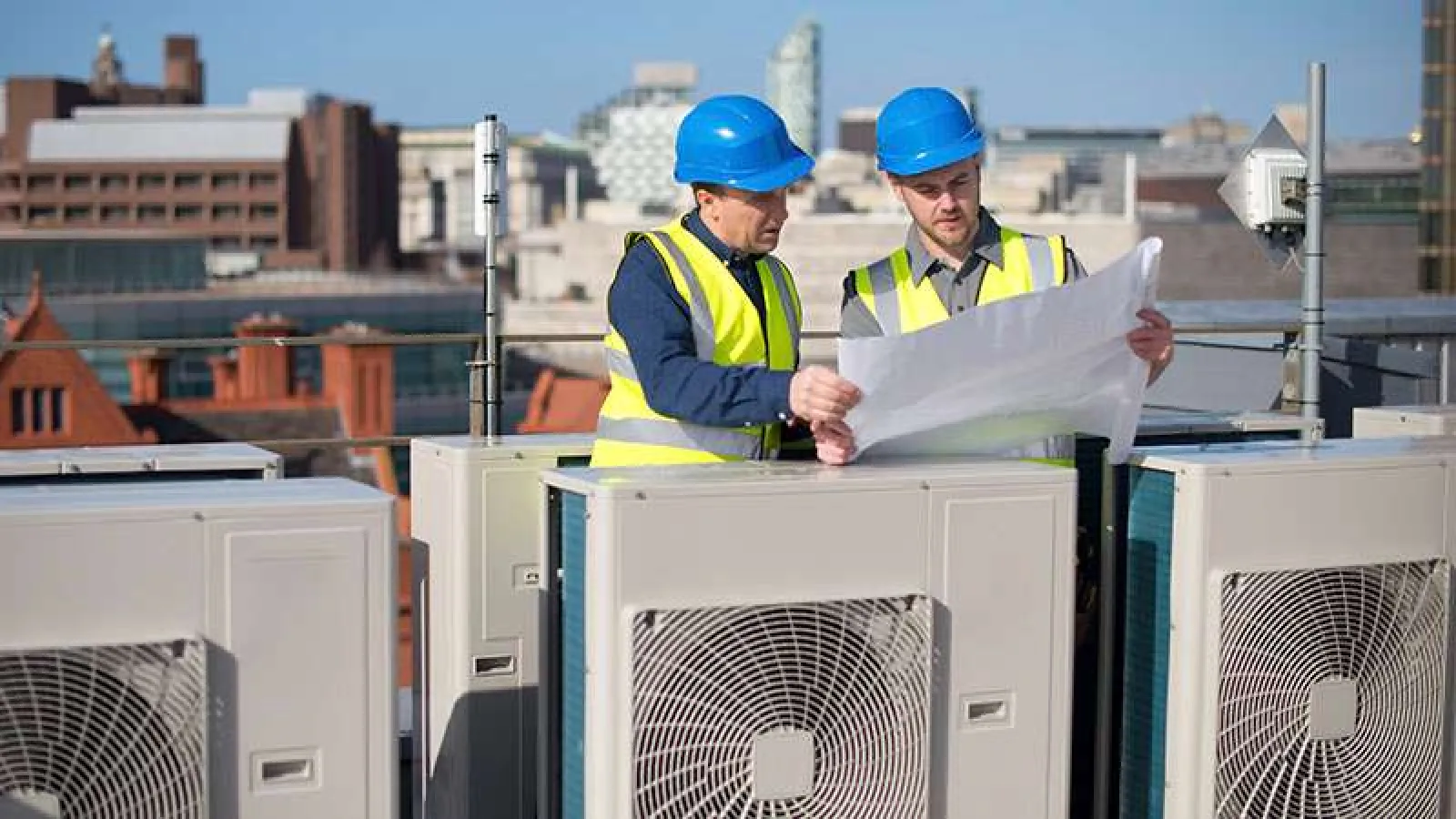 Technician with glasses inspecting and repairing an outdoor HVAC unit during daytime.
