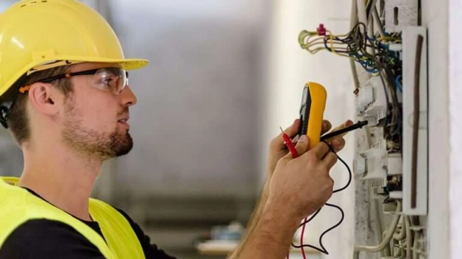 Hand pressing the power switch on a white electric heater in a cozy indoor setting.