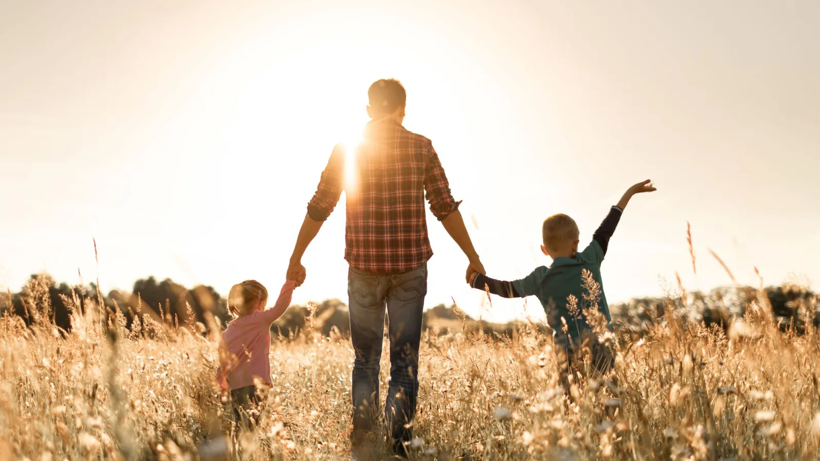 a man and two children running in a field