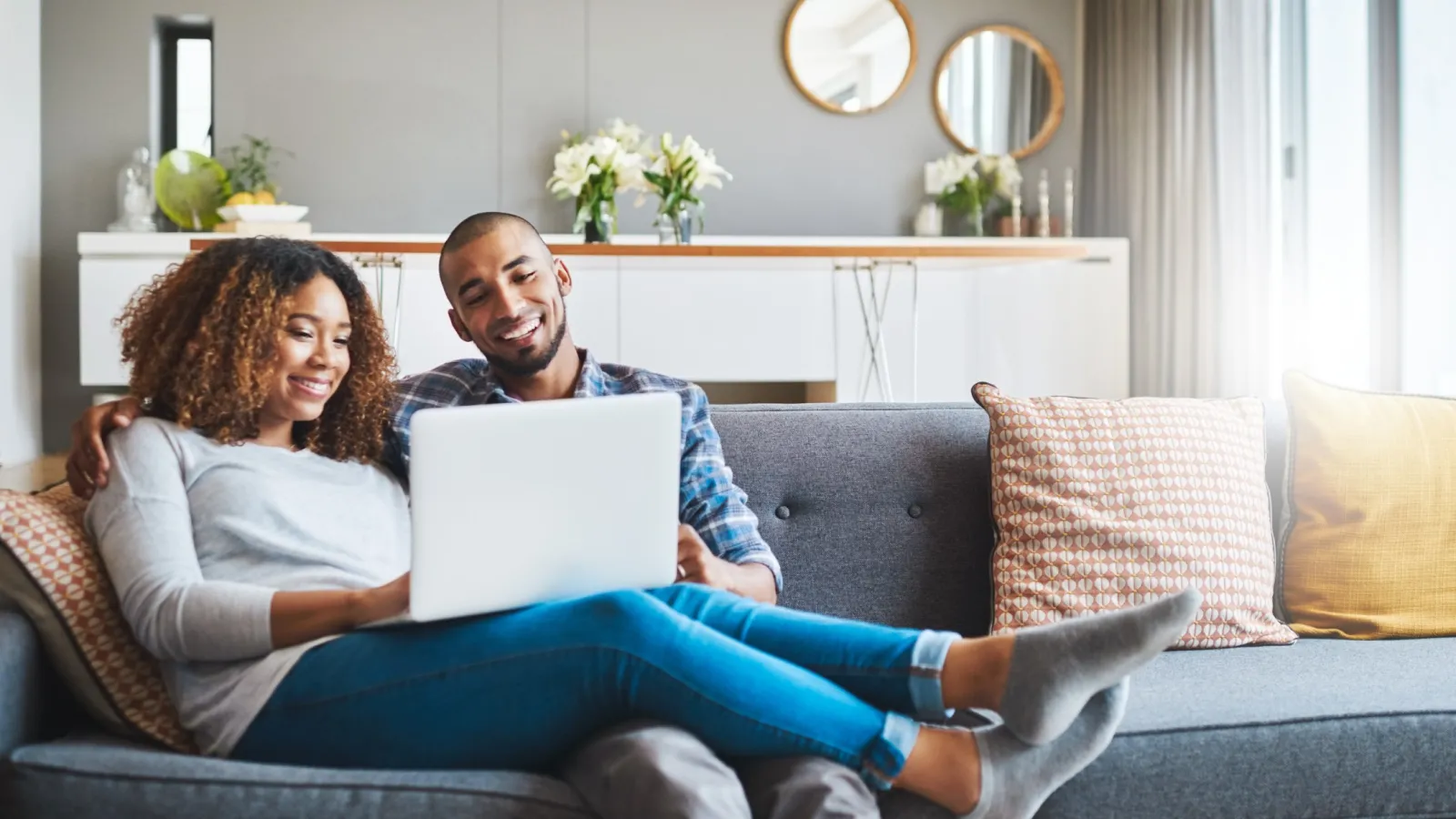 a man and a woman sitting on a couch with a laptop