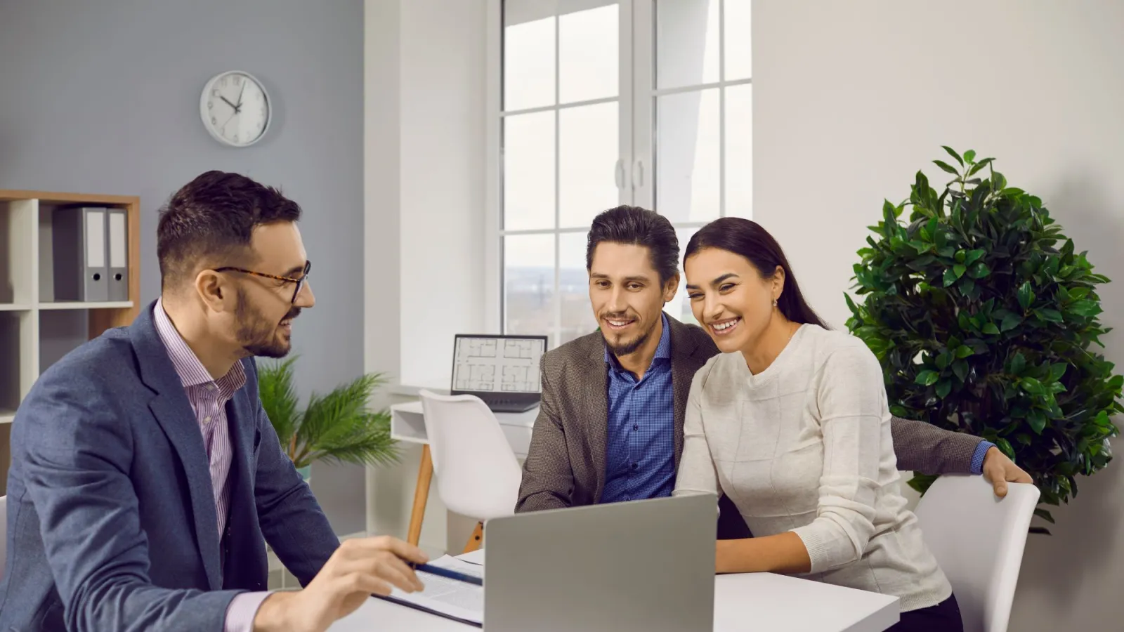 a group of people sitting around a table looking at a laptop