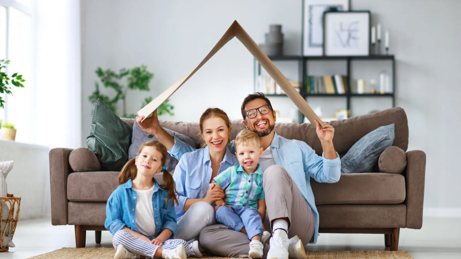 a person and two children sitting on a couch with a wooden object