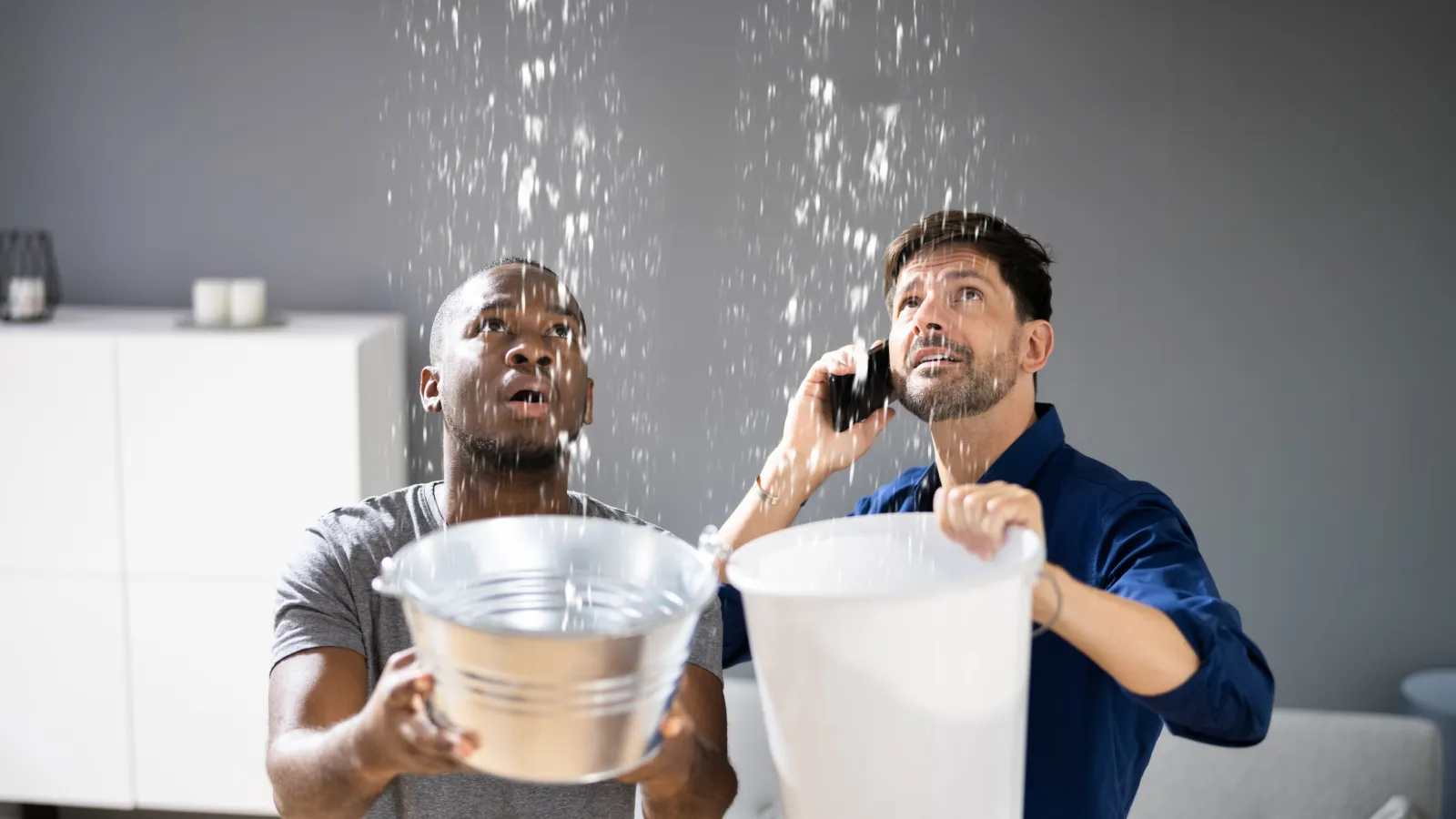 a couple of men holding a bucket of water and talking on the phone