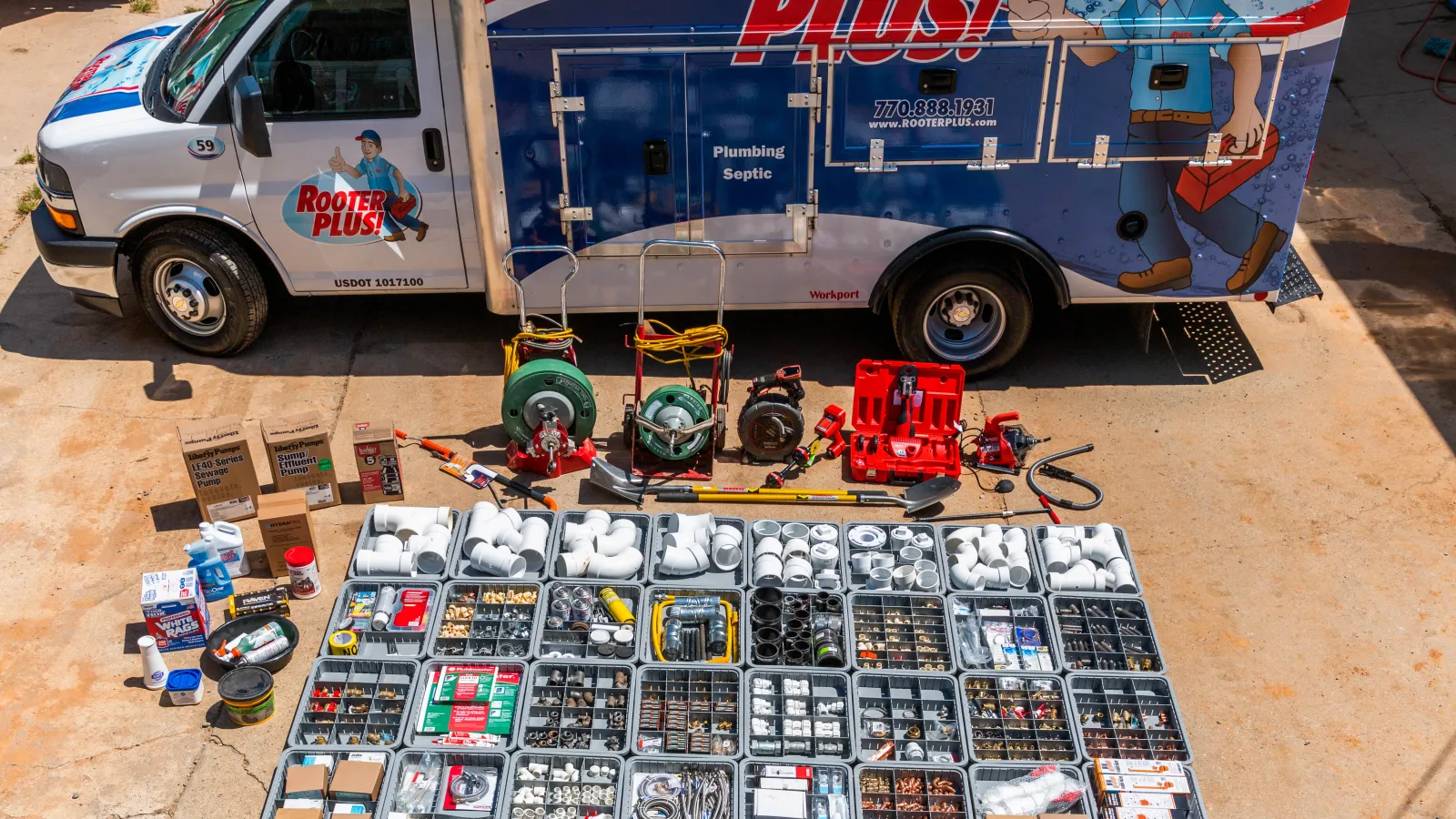 Rooter Plus plumbing service van with organized plumbing tools and parts displayed in front of it.