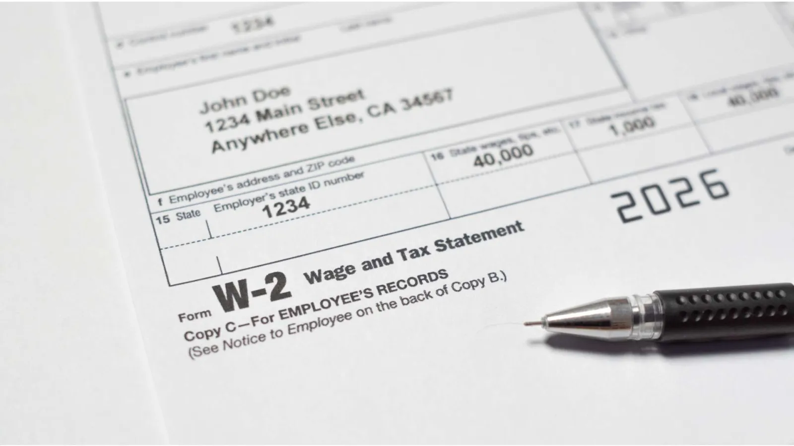 Close-up of a W-2 wage and tax statement form with a pen on a white surface.