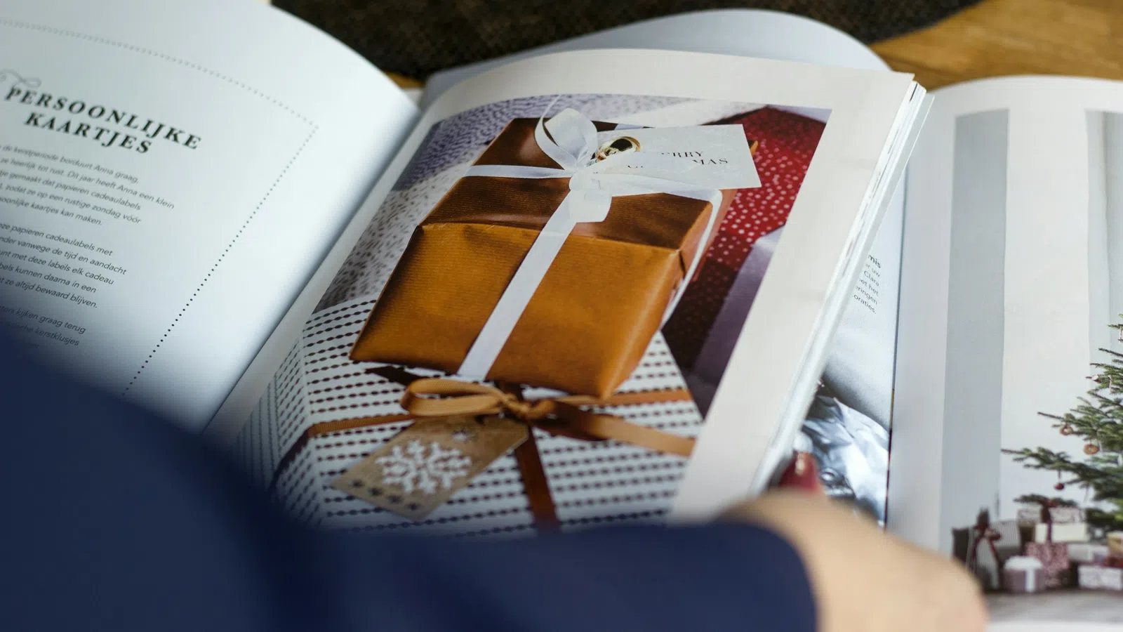 Open magazine showing a page with photo of wrapped gifts, a Christmas tree, and holiday decor.