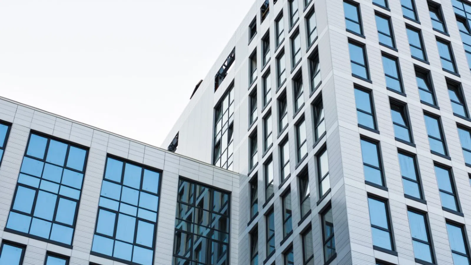Modern white office building with large blue-tinted windows under a clear sky