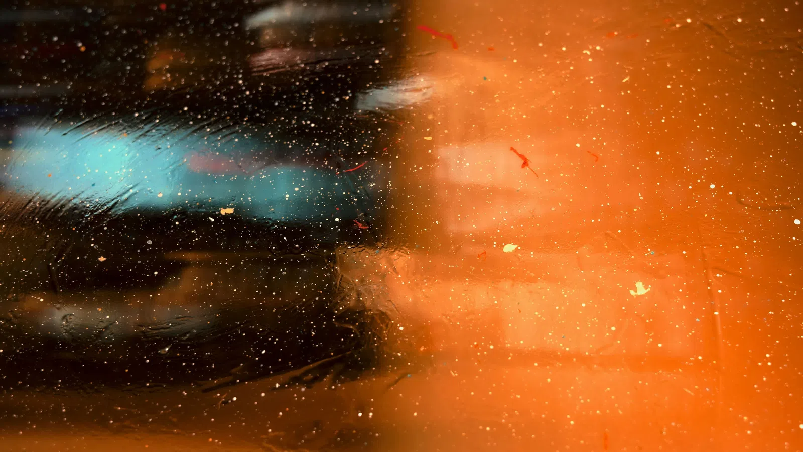 Abstract orange and blue background with scattered sparks and light reflections creating a textured effect