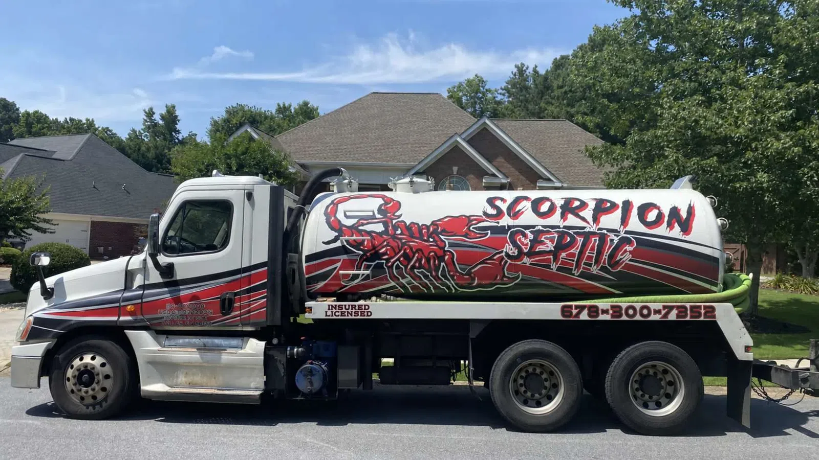 Septic service truck with red scorpion logo and Scorpion Septic text parked on suburban street in front of a house.