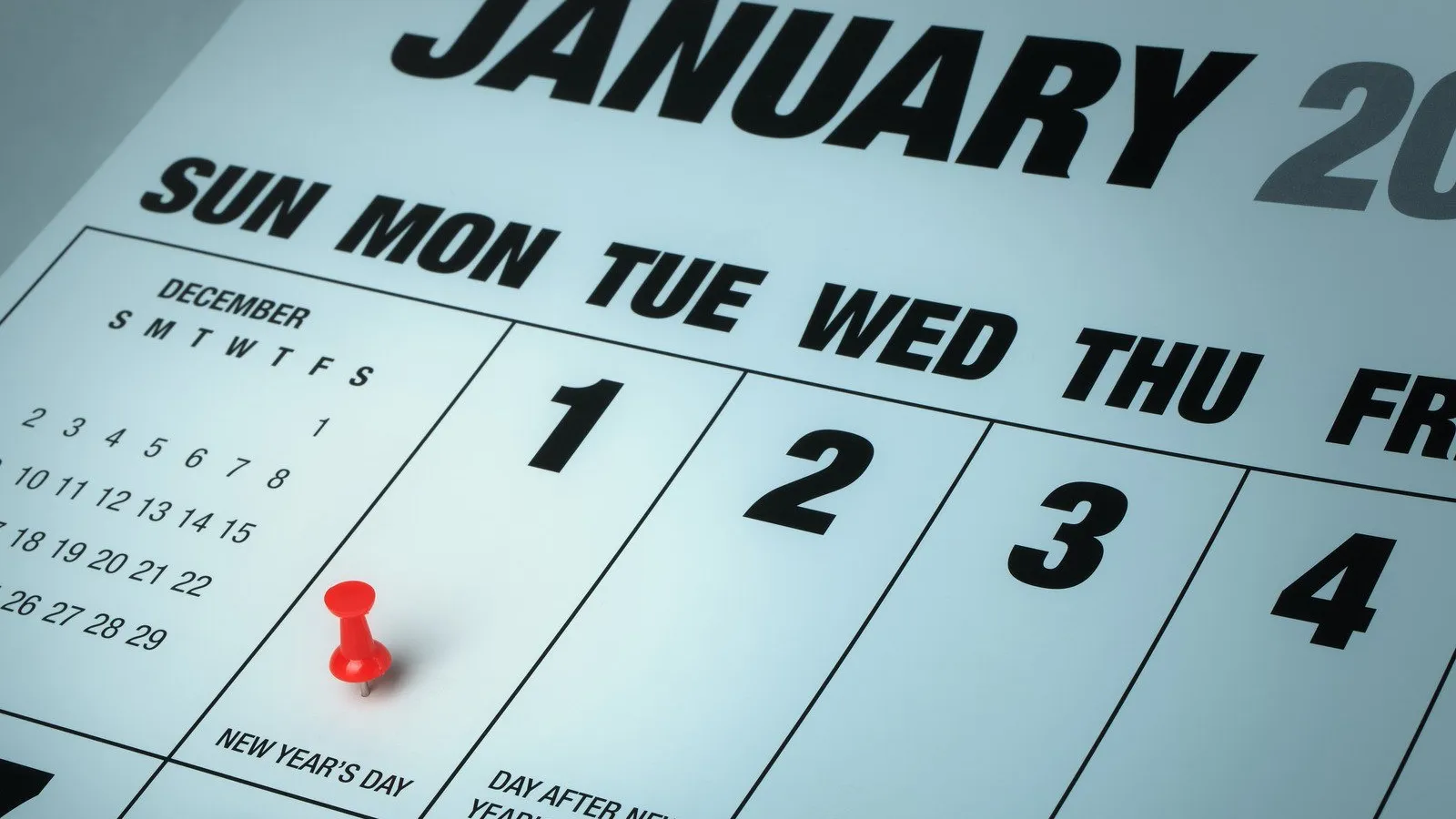 Close-up of January calendar with a red pushpin marking New Year's Day on January 1st.