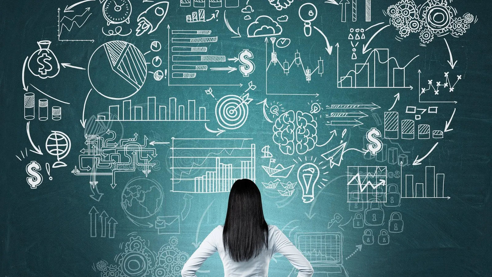 Businesswoman analyzing financial charts and graphs drawn on a chalkboard, symbolizing strategy and growth planning.