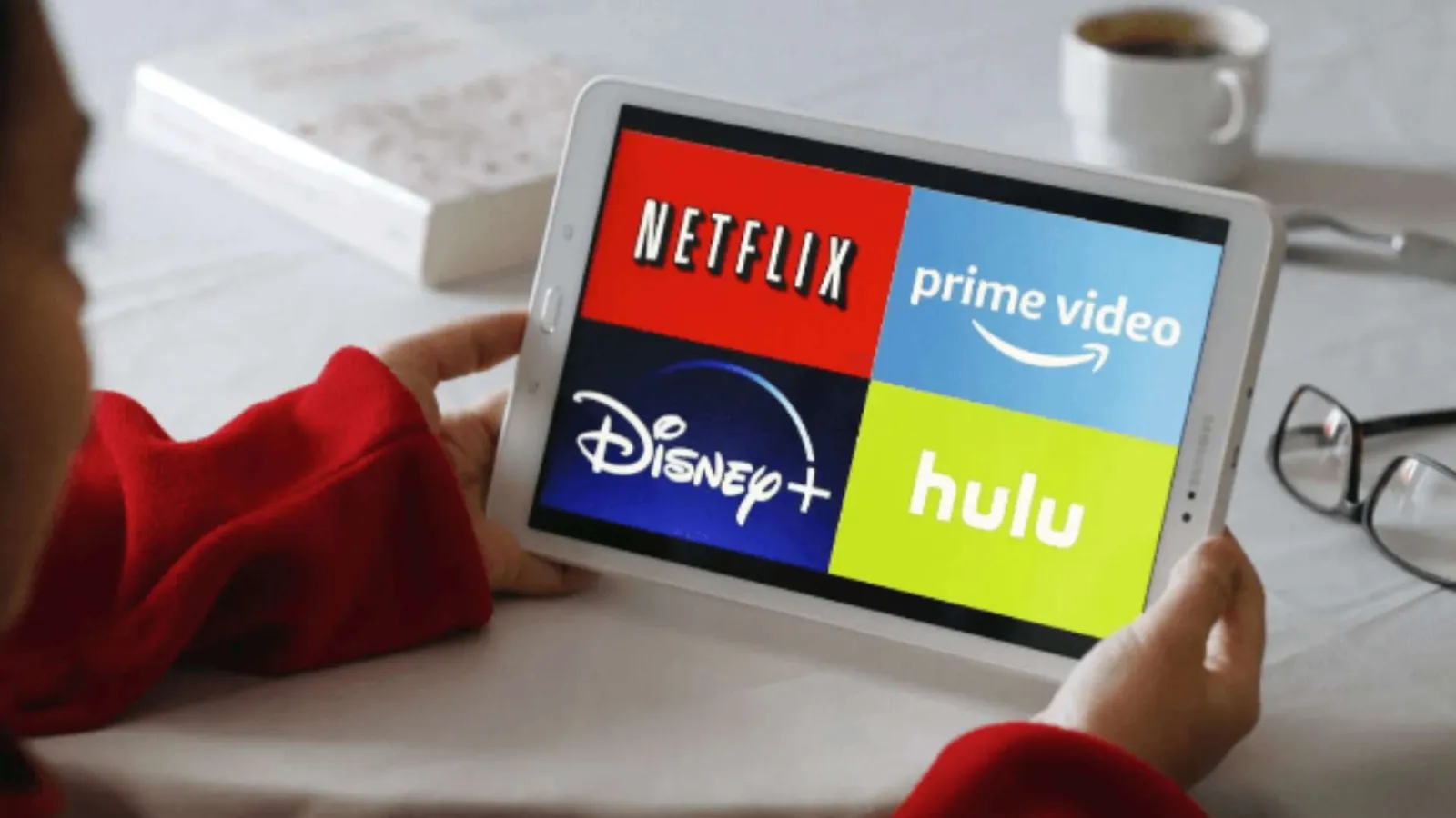 Person holding a tablet displaying Netflix, Prime Video, Disney+, and Hulu streaming service logos.