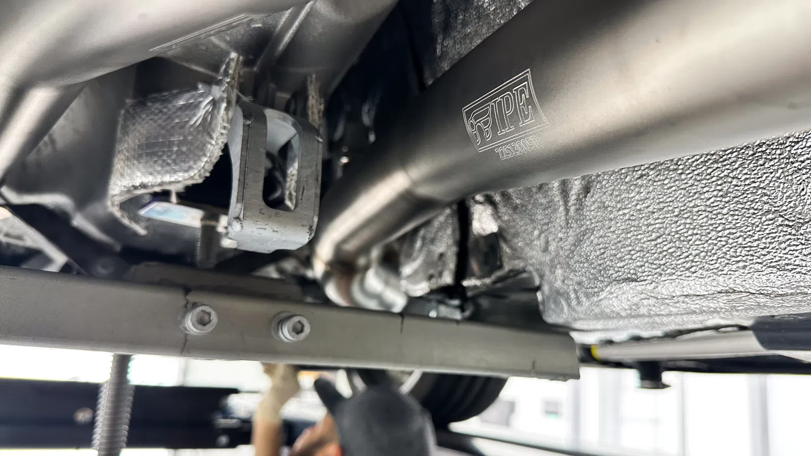 Close-up of car exhaust system and undercarriage with stainless steel IPF piping and mounting bracket.