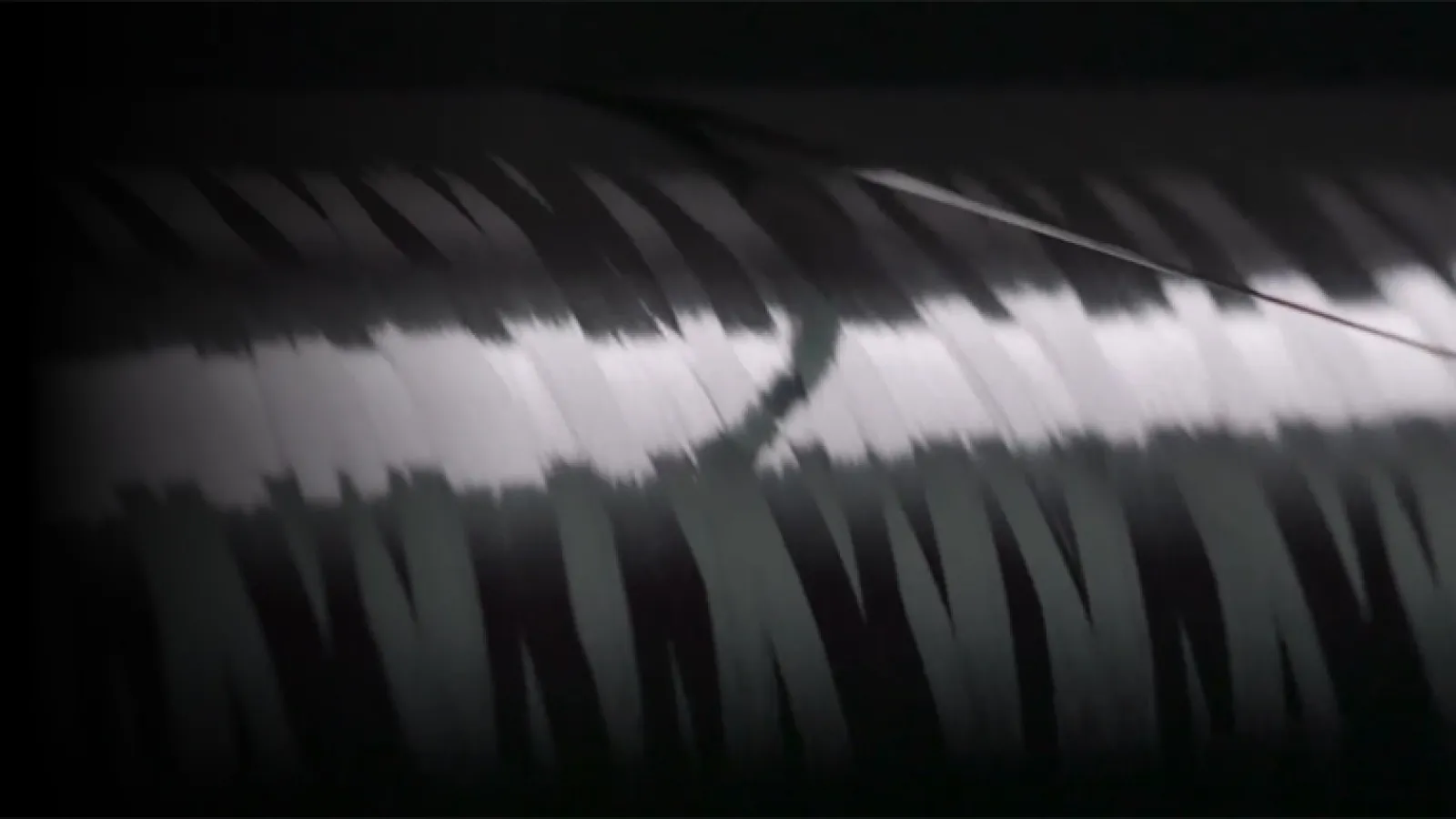 Close-up of a shiny, metallic cylindrical object with reflective light streaks and dark shadows