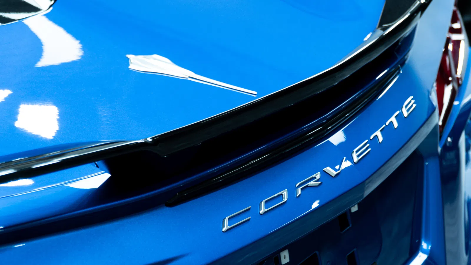 Close-up of blue Corvette car rear with chrome Corvette lettering and sleek black spoiler detail