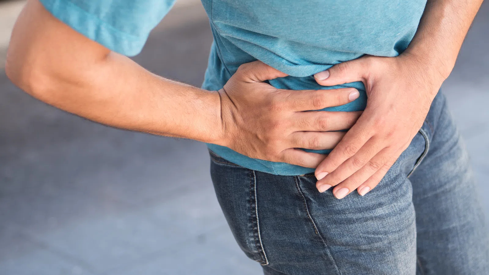 Person clutching right hip and lower abdomen, indicating pain or discomfort in that area.