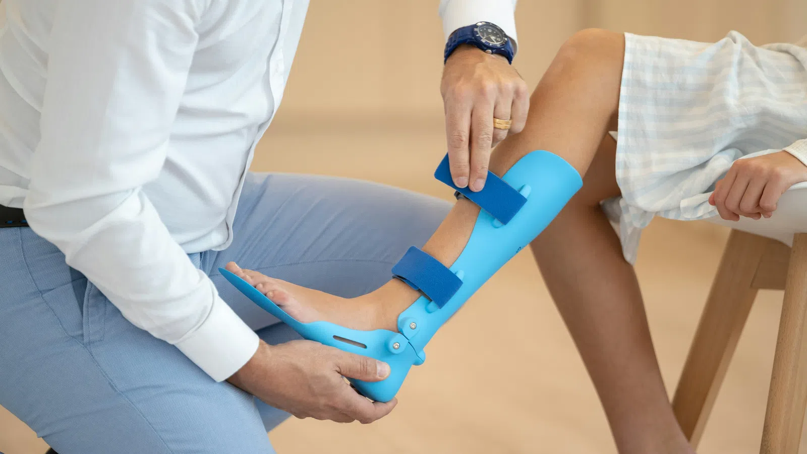 Orthopedic specialist fitting blue leg brace on child's leg for support and recovery.