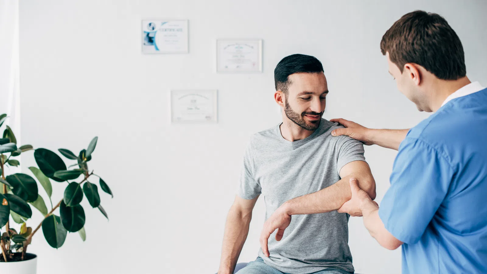 Physiotherapist examining and guiding a patient's arm movement during a physical therapy session in a clinic