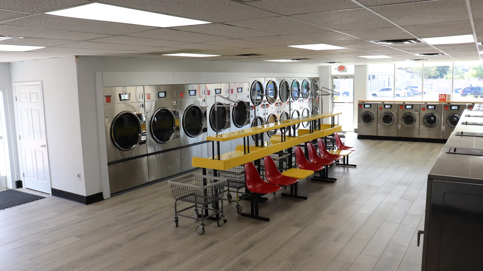 a room with a row of washing machines and chairs
