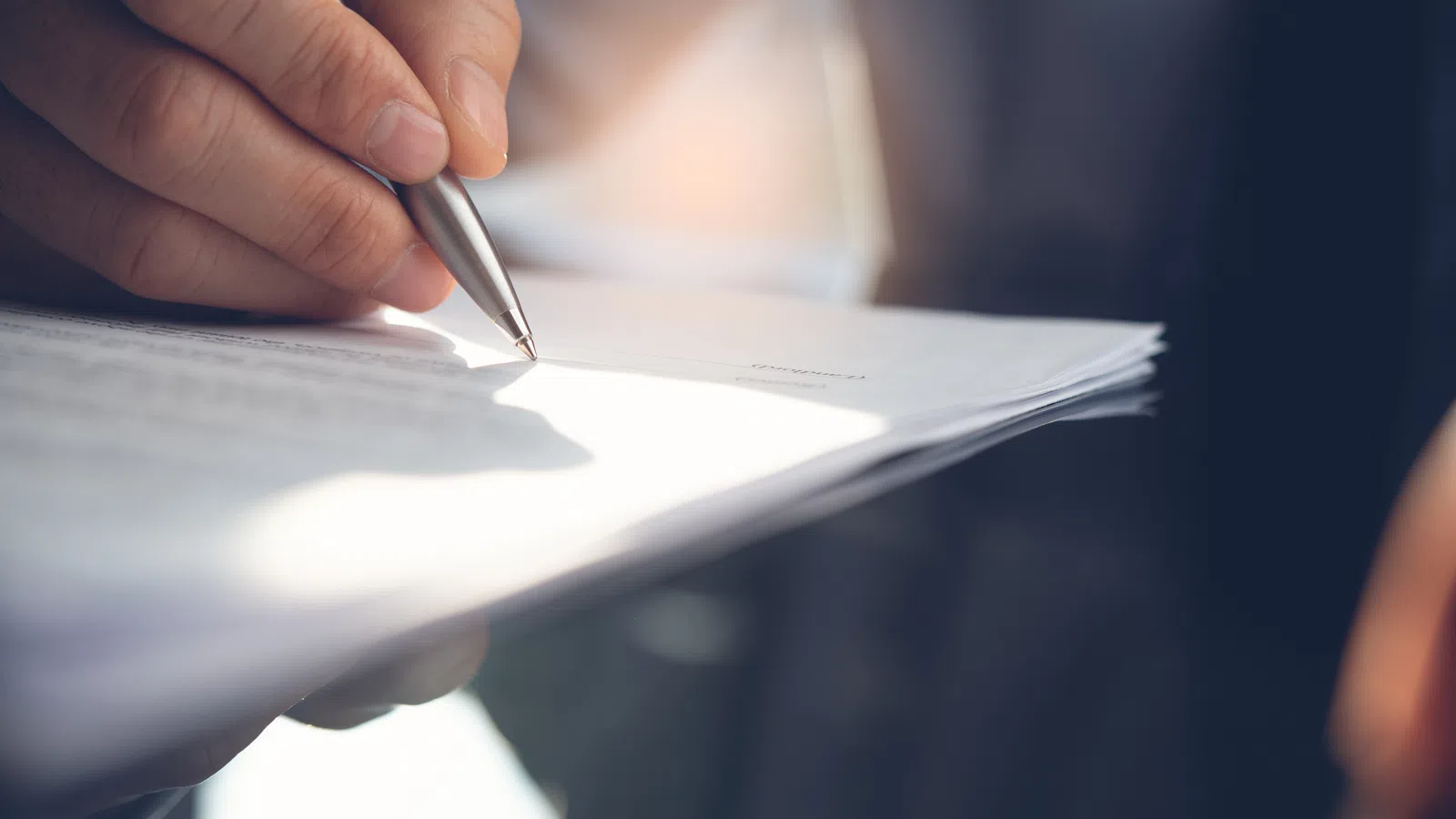 a person signing a piece of paper with a pen