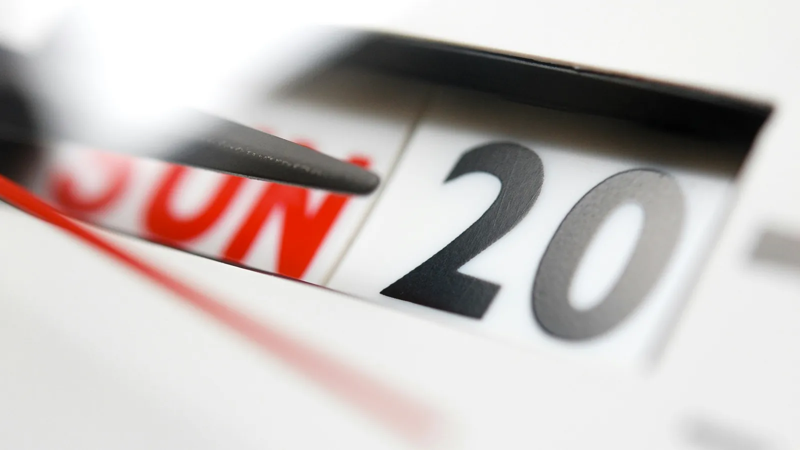 Close-up of a calendar showing Sunday the 20th with a clock hand nearby indicating time.