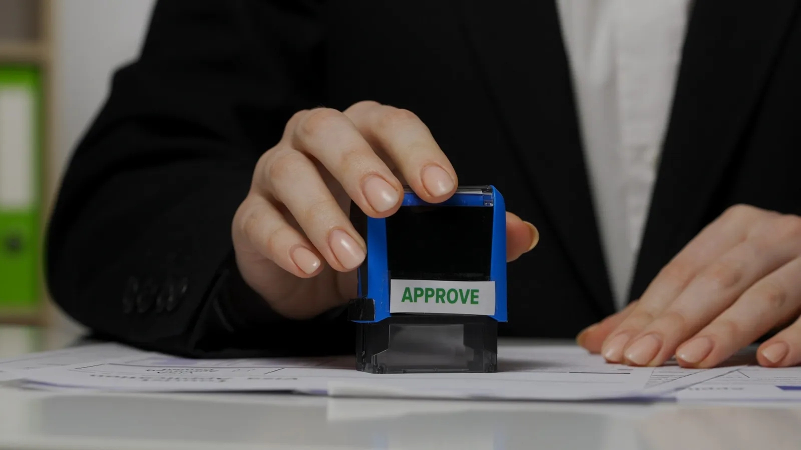 A person using an approval stamp on documents in a professional setting.