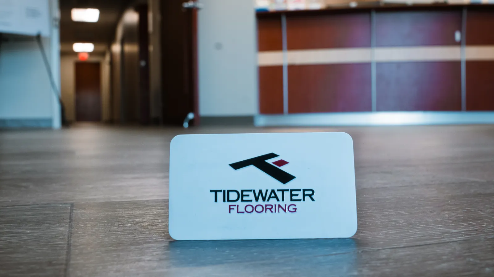 Card displaying Tidewater Flooring logo on a wood floor in a professional setting.