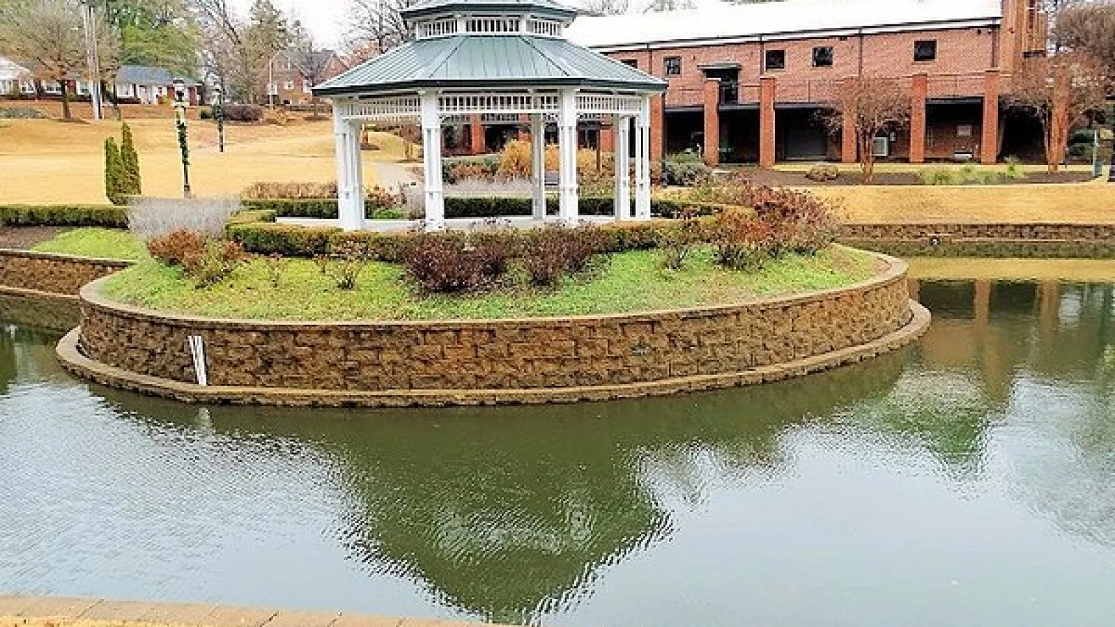 brick building with gazebo and pond