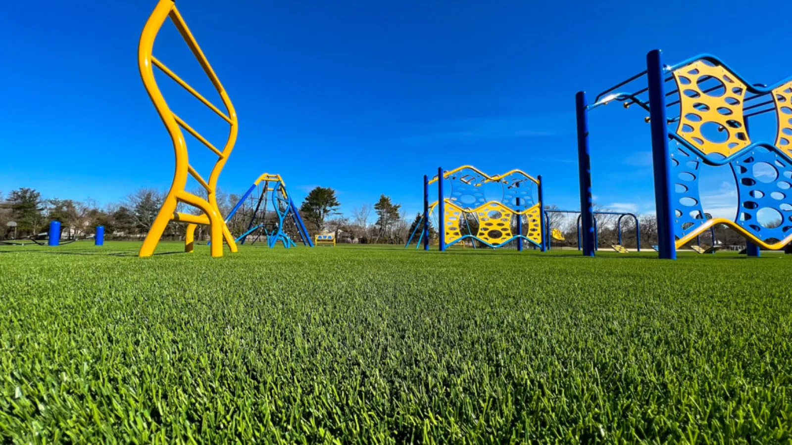 a grassy field with a playground in the background