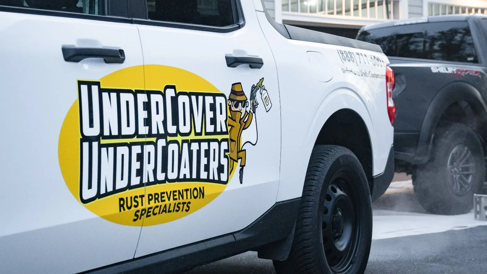 White UnderCover UnderCoaters truck parked outside a home with garage and holiday lights in the evening.