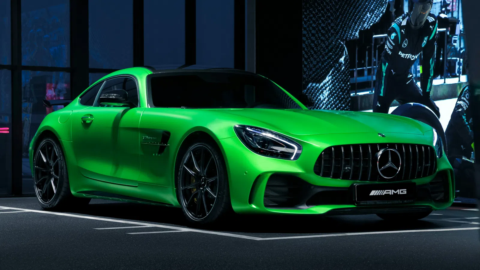Vibrant green Mercedes AMG sports car parked with sleek design and dark tinted windows under dramatic lighting.