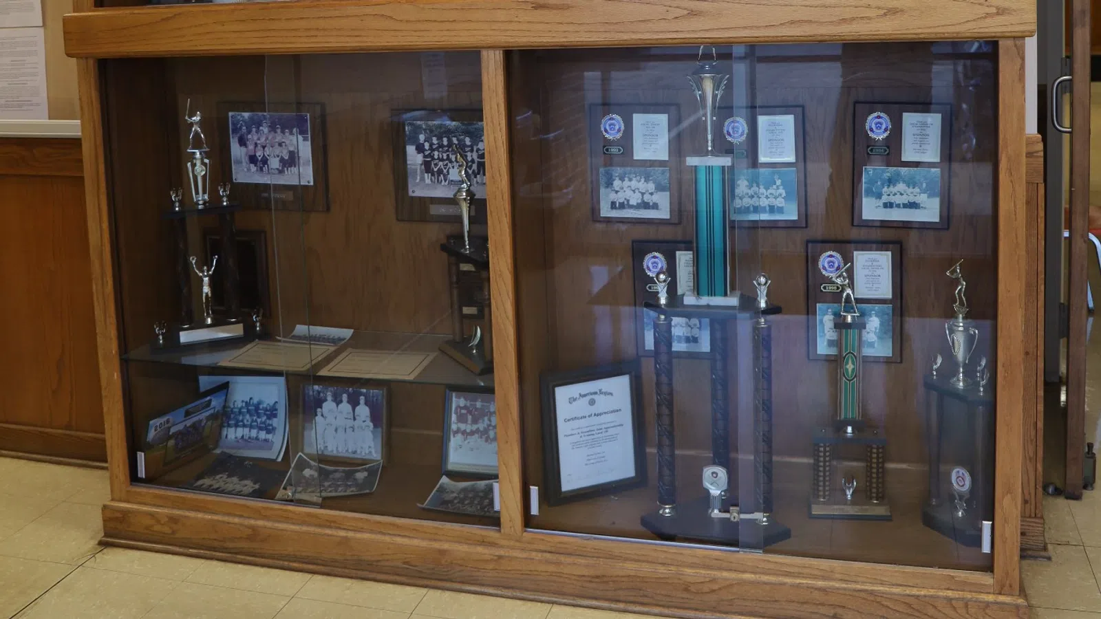 Display case featuring awards, trophies, and plaques in a well-lit office environment.