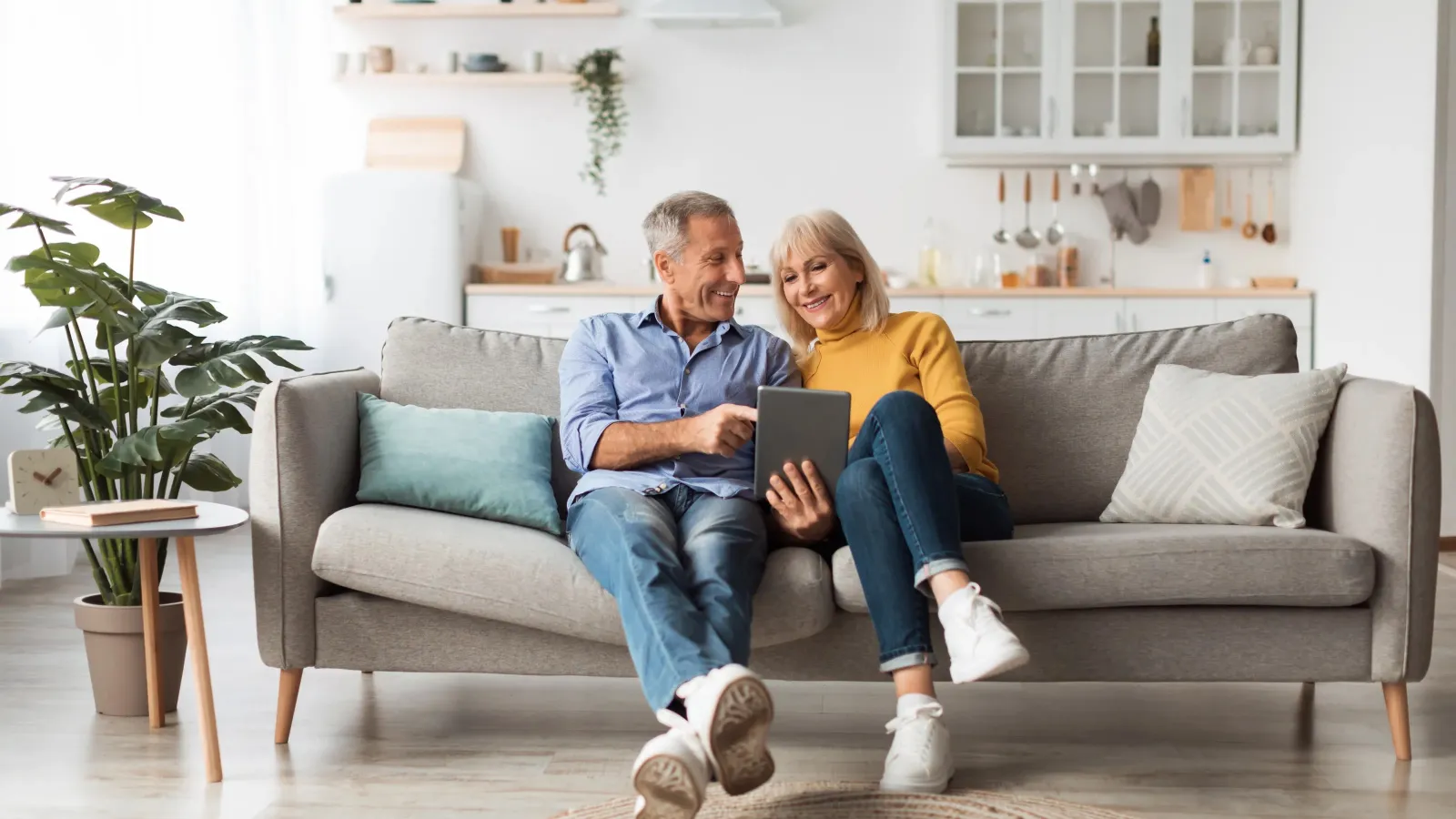 a man and a woman sitting on a couch looking at a laptop