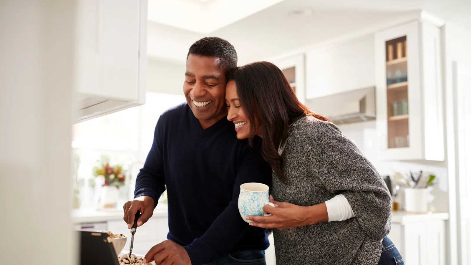 A happy couple prepares dessert together in a bright, modern kitchen, sharing smiles and a cozy moment.