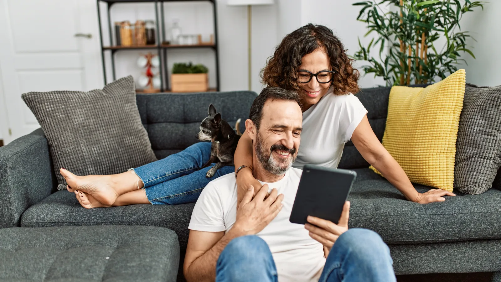 a man and woman sitting on a couch with a cat on his lap