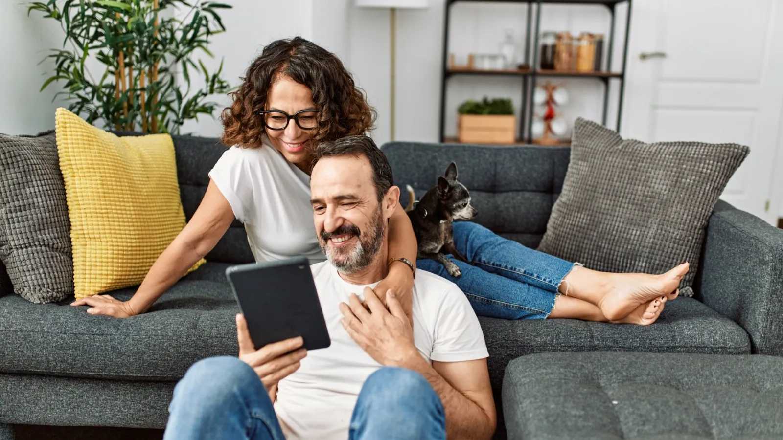 a man and woman sitting on a couch with a cat on his lap