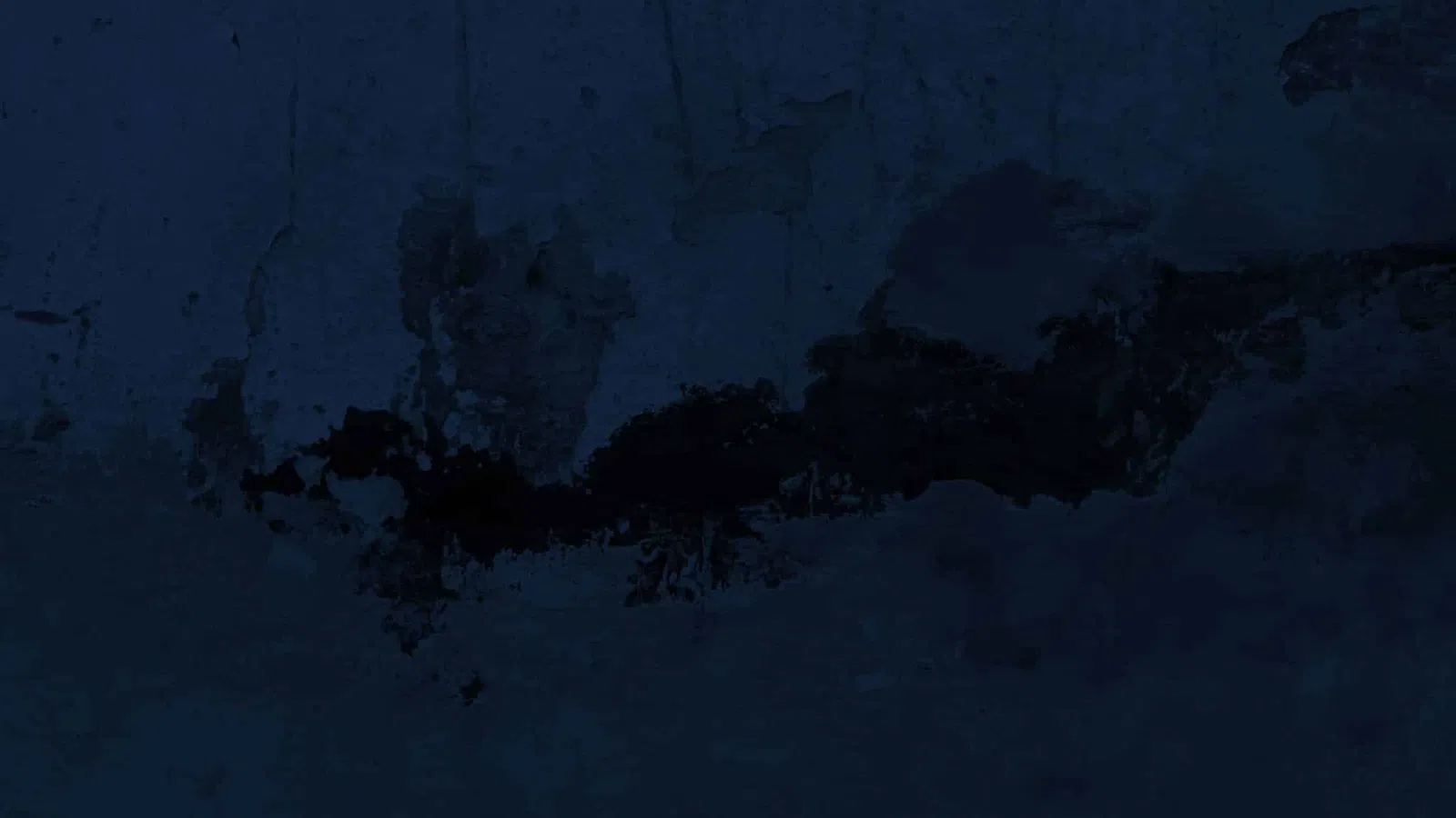 Dark blue textured wall with patches of black peeling paint and rough surface details.