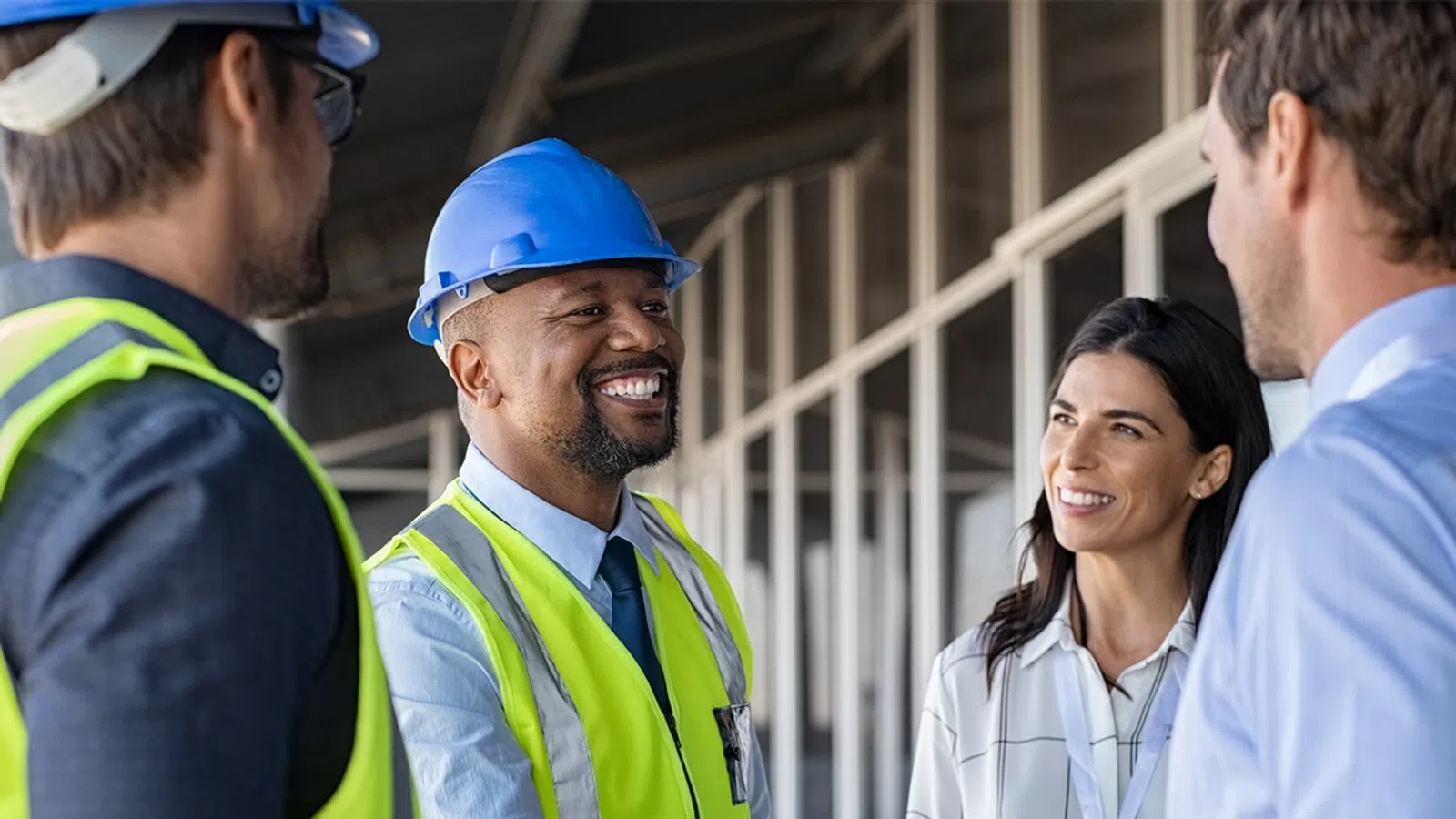 Construction workers and business professionals shaking hands at a building site showing collaboration and teamwork