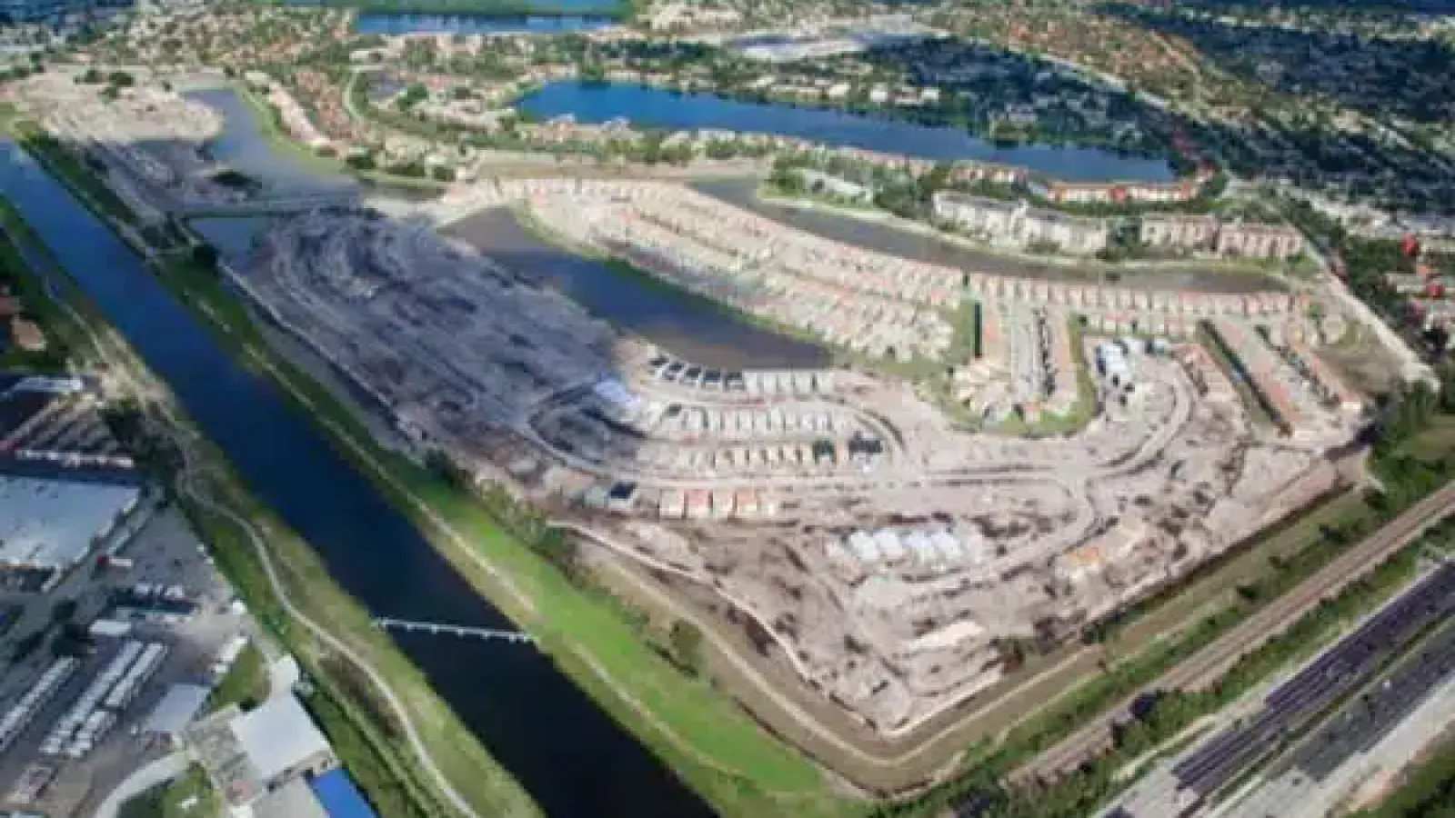 Aerial view of a residential neighborhood under development with waterways and a nearby highway.