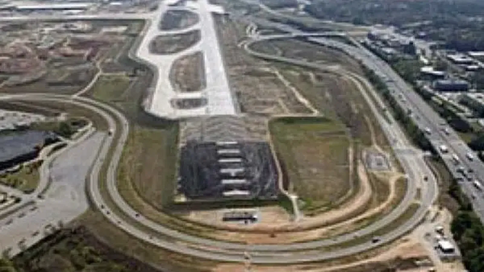 Aerial view of a large highway interchange and surrounding urban and industrial areas on a clear day.